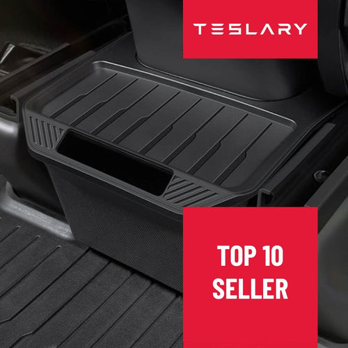 A black plastic car footwell storage organizer tray placed on a vehicle floor mat, with red promotional badges reading TESLARY and TOP 10 SELLER. TESLA_MODEL_Y_MODEL_Y_JUNIPER_REAR_STORAGE_BIN_BUY_FROM_EUROPE_AND_IRELAND_TESLARY.EU_TESLARY.IE_TESLARY.CO.UK_TESLARY.PT_TESLARY.ES